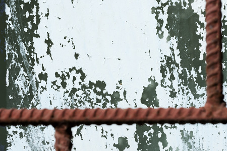 Old painted window behind iron bar close up. Grunge background