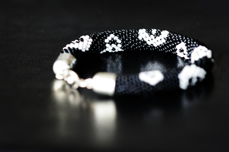 Black beaded bracelet with skull image on a dark background close upの写真素材