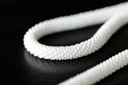 White long beaded necklace on a dark backgroun close up