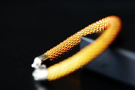 Yellow bracelet made of transparent shiny seed beads on a dark background close upの写真素材
