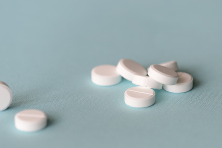 White tablets scattered on a blue background close up