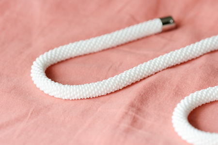 White beaded necklace on a textile background coral color close upの写真素材