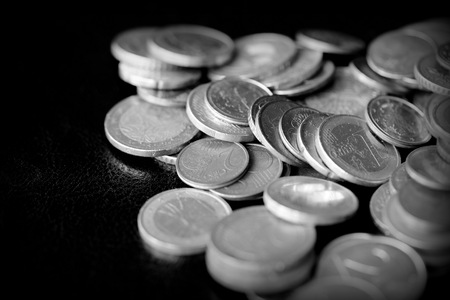 Euro coins scattered on a dark surface close up. Black and whiteの写真素材