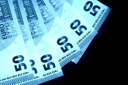 Fifty euro notes on a dark background close up. Blue color toned