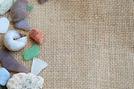 Sea glasses, shells and stones on a rough woven background close-up. Vacation conceptの写真素材