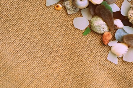 Shells, sea glasses and stones on a jute background close-up brown color toned. Vacation conceptの写真素材