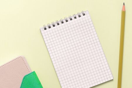 Blank notepad, organizer and pencil on a yellow background close up