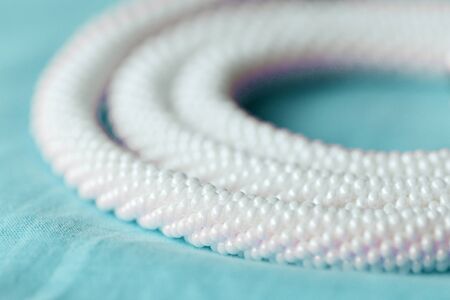 White beaded necklace on a blue textile background close upの写真素材
