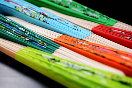 Set of folded multi-colored Vietnamese fans on a dark background close-up