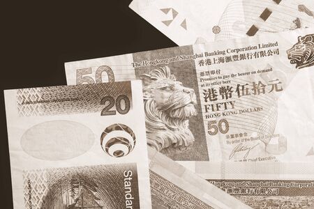 Different Hong Kong dollars bills on a dark background close up. Money background brown color tonedの写真素材