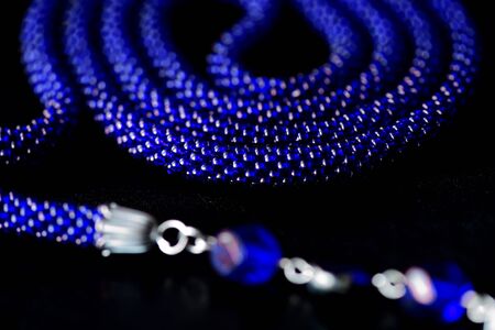 Long open necklace (lariat) blue color on a dark background close upの写真素材