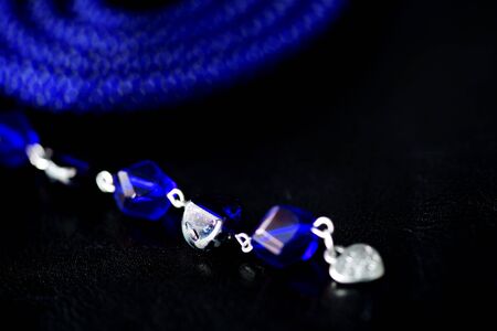 Long open necklace (lariat) blue color on a dark background close upの写真素材