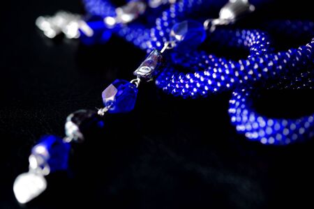 Long open necklace (lariat) blue color on a dark background close upの写真素材