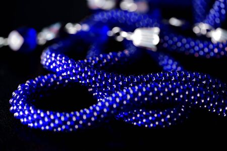 Long open necklace (lariat) blue color on a dark background close upの写真素材