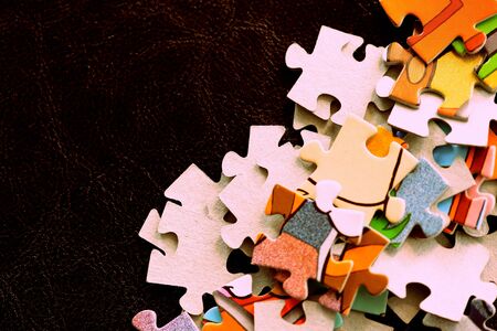 Children's puzzles on a dark surface close-up, brown color tonedの写真素材