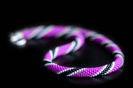 Beaded necklace purple, black and white colors on a dark background close upの写真素材
