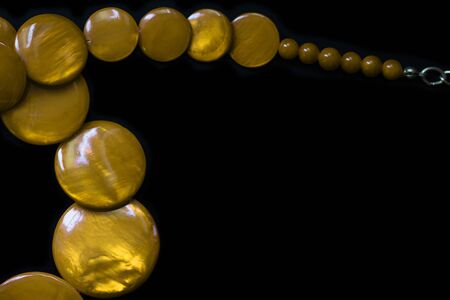 Yellow necklace made of round flat beads on a dark background close upの写真素材