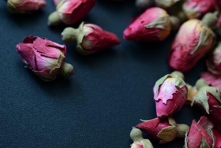 Dried rose buds scattered on a dark surface. Rose tea close upの写真素材