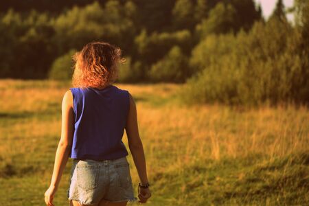 Lovely young girl on a walk in the forest lit by the evening sun. The concept of happiness, youth and beauty of natureの写真素材