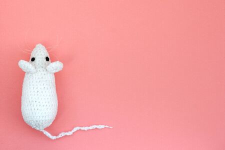 White crocheted rat on a pink background. Mouse symbol 2020 new year. Top view, copy space