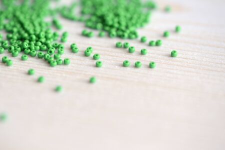 Green color seed beads scattered on the wooden background close-upの写真素材