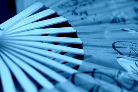 Vietnamese fan spread out on a dark background close-up. Blue color tonedの写真素材