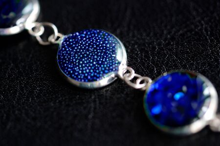 Resin bracelet with blue glitters on a dark surface close-upの写真素材