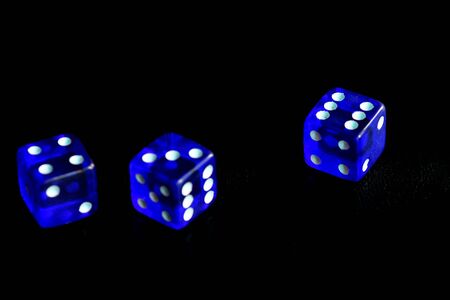 Blue dice scattered on a black surface close-up. Gambling background