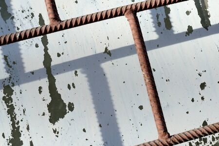 Old window painted by white paint behind a rusty brown bars on a sunny day. Abstract background