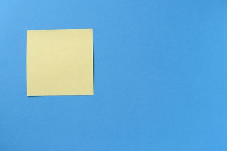 Blank yellow sticker note on a blue background with copy space. Business concept, horizontal mock-up