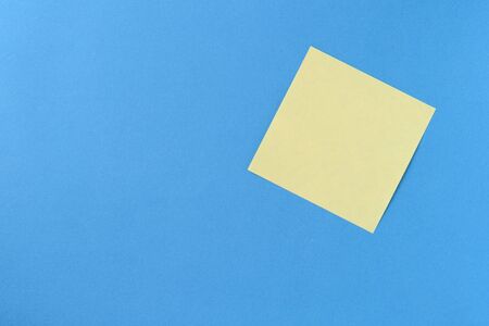 Blank yellow sticker note on a blue background with copy space. Business concept, horizontal mock-upの写真素材