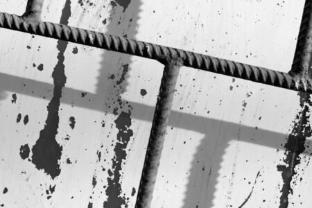 Fragment of an old painted window behind a rusty bars on a sunny day. Monochrome abstract backgroundの写真素材