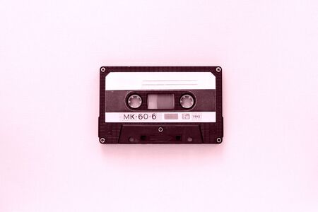 Old audio tape cassette close-up. Old technology concept. Pink color toned