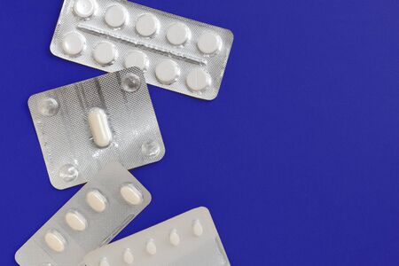 Tablets blisters on a deep blue background. Top view , copy space. Pharmacy concept