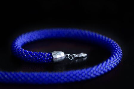 Bead crochet necklace blue color a dark surfce close up. Fashion background
