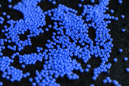 Seed beads blue color scattered on a dark background close up. Handmade and handwork conceptの写真素材