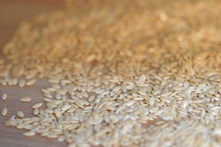Closeup of flax seeds scattered on a wooden surface. Healthy food backgroundの写真素材