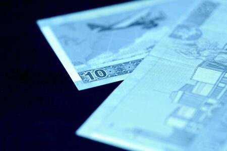 Two Lithuanian banknotes on a dark surface. Ten and twenty litas close-up. Money background blue...
