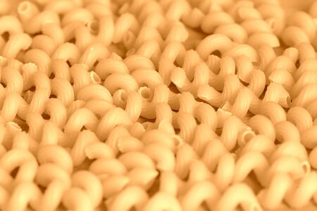 Spiral pasta scattered on a wooden surface close-up. Healthy food background brown color tonedの写真素材