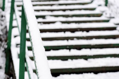 Green stairs covered with snow after a snowfall on a city street on a winter day