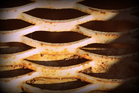 Old rusty iron grid illuminated by the sun close up. Abstract background retro style toned
