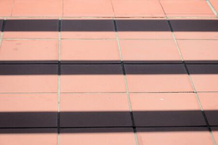 Brown tile on the floor with stripes of shadow on it. Abstract backgroundの写真素材
