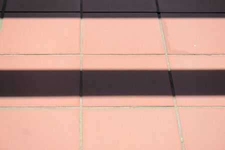 Brown tile on the floor with stripes of shadow on it. Abstract backgroundの写真素材