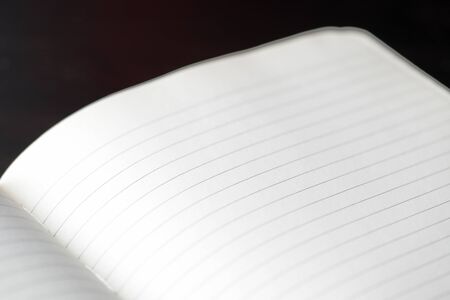 Open blank notebook with lined pages on a dark background close-up. Educational or business conceptの写真素材