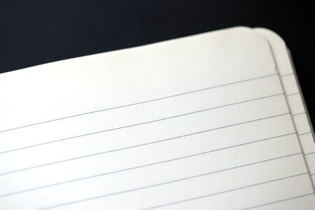 Open blank notebook with lined pages on a dark background close-up. Educational or business conceptの写真素材