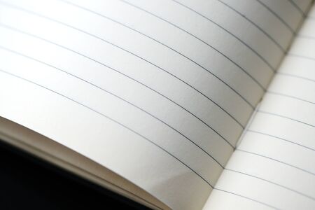 Open blank notebook with lined pages on a dark background close-up. Educational or business conceptの写真素材