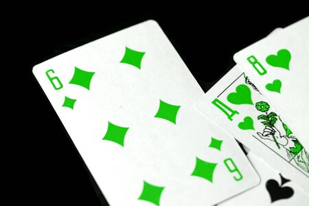 Playing cards unusual green color scattered on a black surface close-up. Gambling backgroundの写真素材