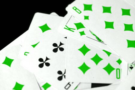 Playing cards unusual green color scattered on a black surface close-up. Gambling backgroundの写真素材