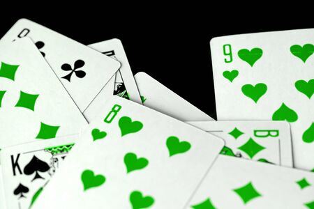 Playing cards unusual green color scattered on a black surface close-up. Gambling backgroundの写真素材