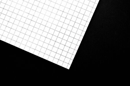 Fragment of a checkered notebook on a black background close-up. Top view. Office conceptの写真素材